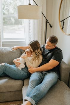 a man and woman sitting on a couch holding a baby