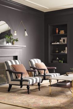 a living room with two chairs and a coffee table in front of a fire place