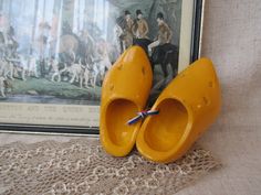 a pair of yellow shoes sitting on top of a table next to a framed painting