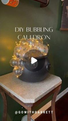 there is a bowl on top of a table with lights in the corner and words above it that read diy bubbling cauldron