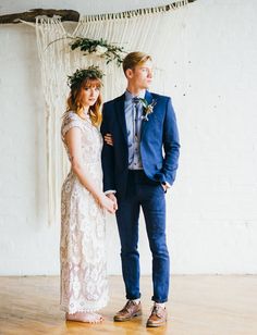 a young man and woman standing next to each other in front of a white wall