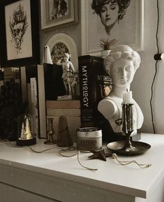 a white busturine sitting on top of a table next to books and candles