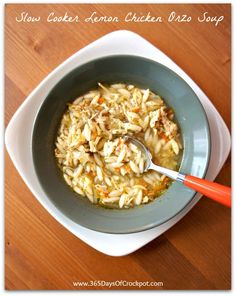 a bowl of chicken noodle soup with a spoon in it on a wooden table