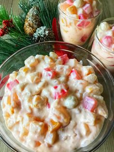 a bowl filled with fruit salad next to two small glass bowls full of candy and pine cones