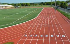 an empty track with numbers painted on it in the middle of a grassy area next to a field