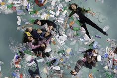 several people floating in the water surrounded by plastic bottles and other trashcans, with one person laying on the floor