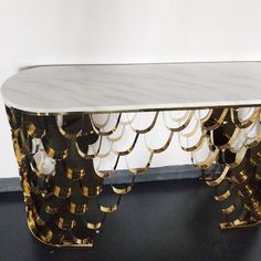 a table with gold and white decorations on the top, in front of a wall