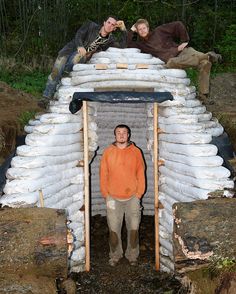 a man standing in front of a small structure made out of sandbags and bags