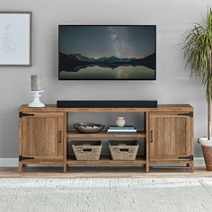 a living room scene with focus on the entertainment center and wall hangings above it