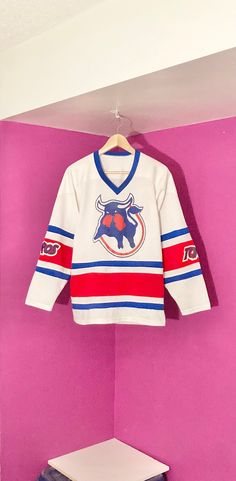 This jersey was made for former-WHA team the Toronto Toros. This jersey is the white home jersey for the team and has screenprint logos for the Toros and a screenprint #13 on the back. This is a mesh-style jersey as the pictures show. This jersey is in good condition with no rips, tears, or major stains. A handful of marks on back on bottom that were mostly removed. A few pinholes here and there as well. Overall great for a collector! Size: Size tag missing (probably about a Men's Small) 21" wid Collegiate Cotton Jersey For Fans, Collegiate Cotton Jersey For Fan Gear, White Letter Print Jersey For Game Day, Throwback Team-colored Cotton Jersey, Varsity Jersey With Team Logo For Sports Season, Varsity Jersey With Team Logo, White Jersey With Team Name For Game Day, White Team Spirit Jersey For College, Cotton Team Jersey Fan Apparel