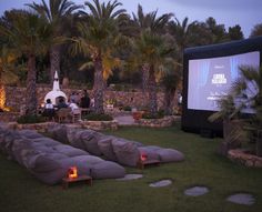 an outdoor movie is set up on the lawn with bean bag chairs and palm trees