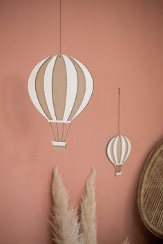 two hot air balloons are hanging from the wall next to some pamodia plants