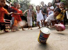 a can of beer sitting on the ground in front of some children playing with it