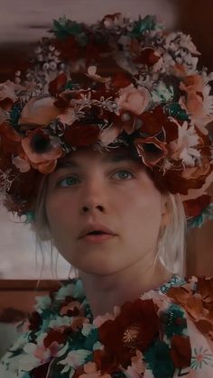 a woman with flowers on her head wearing a flower crown in front of her face