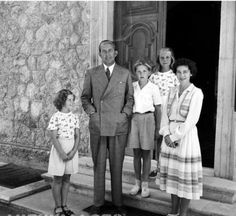 an old black and white photo of people standing in front of a door with their children