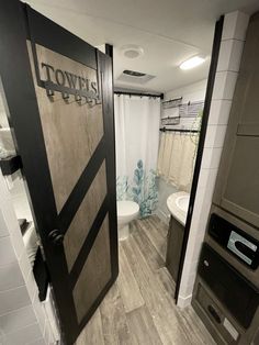 a bathroom with an open door leading to the toilet and sink area in front of it