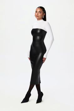 a woman wearing a black and white dress with long sleeves, tights and heels