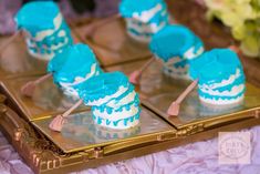 small cupcakes with blue icing are on a tray