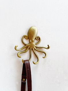 an octopus is hanging on the wall next to a leather belt with a brass buckle