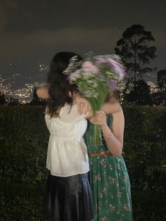 two women standing next to each other with flowers in their hair and one holding the back of another woman's head