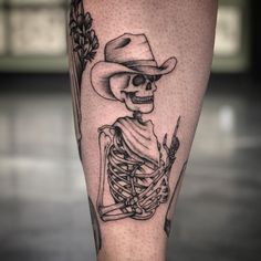 a man with a skeleton tattoo on his leg wearing a cowboy hat and holding a knife