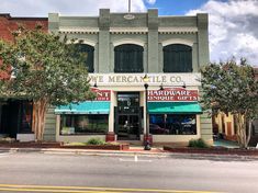 a store front with awnings and trees on the side of the street in front of it