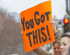 a woman holding up a sign that says you got this