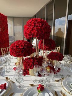 the table is set with red roses and gold place settings