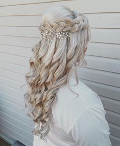 a woman with long blonde hair wearing a braided hairstyle and pearls in her hair