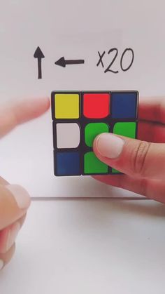 a person is holding a rubik cube in their left hand and pointing at it