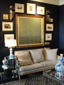 a living room filled with furniture and framed pictures on the wall above it's coffee table