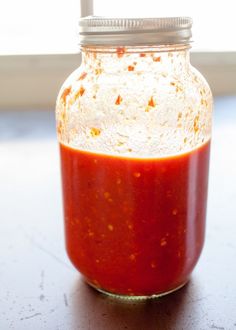 a jar filled with red sauce sitting on top of a table