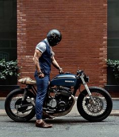 a man in overalls and a helmet standing next to a motorcycle on the street