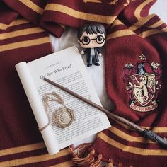 an open harry potter book, necklaces and figurine on top of a blanket