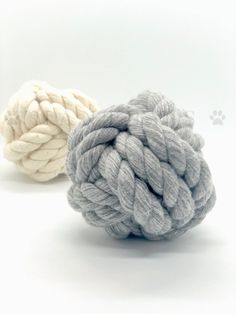 two balls of yarn sitting next to each other on a white surface with paw prints in the background