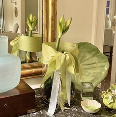 two vases with flowers in them sitting on a table next to a mirror and other items