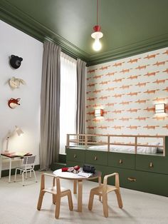 a child's room with green walls and white carpeted flooring, two wooden chairs in front of a small table