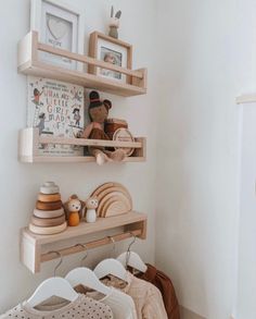 two wooden shelves filled with baby's clothing and toys