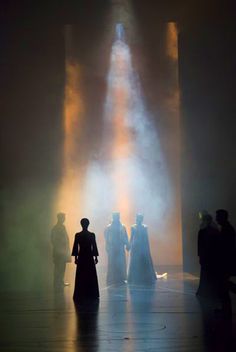 several people standing in the middle of a dark room with light coming from behind them