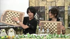 two people are holding up chess boards in front of a table with owls on it