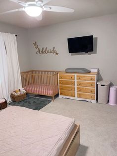 a baby's room with a crib, dresser and television