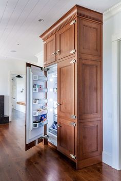 an open refrigerator with its door wide open in a room that has hardwood floors and white walls