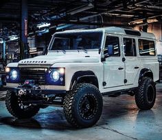 a white land rover is parked in a garage with its lights on and it's front bumper up