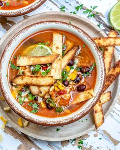 two bowls of mexican soup with tortilla sticks on the side and garnished with cilantro