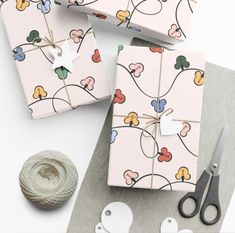 wrapping paper and scissors on top of a table with yarn, twine and crochet hooks