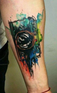 a person with a colorful tattoo on their arm and leg is holding up a camera