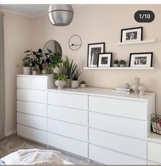 a bedroom with white dressers and pictures on the wall next to plants in vases