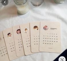 four calendars with pictures on them sitting on a table next to candles and jars