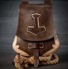 a brown leather backpack sitting on top of a pile of rope