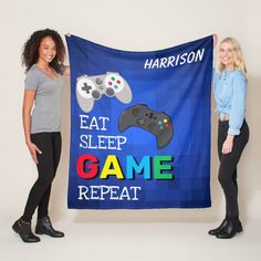 two women holding up a banner that says eat sleep game repeat with video game controllers on it